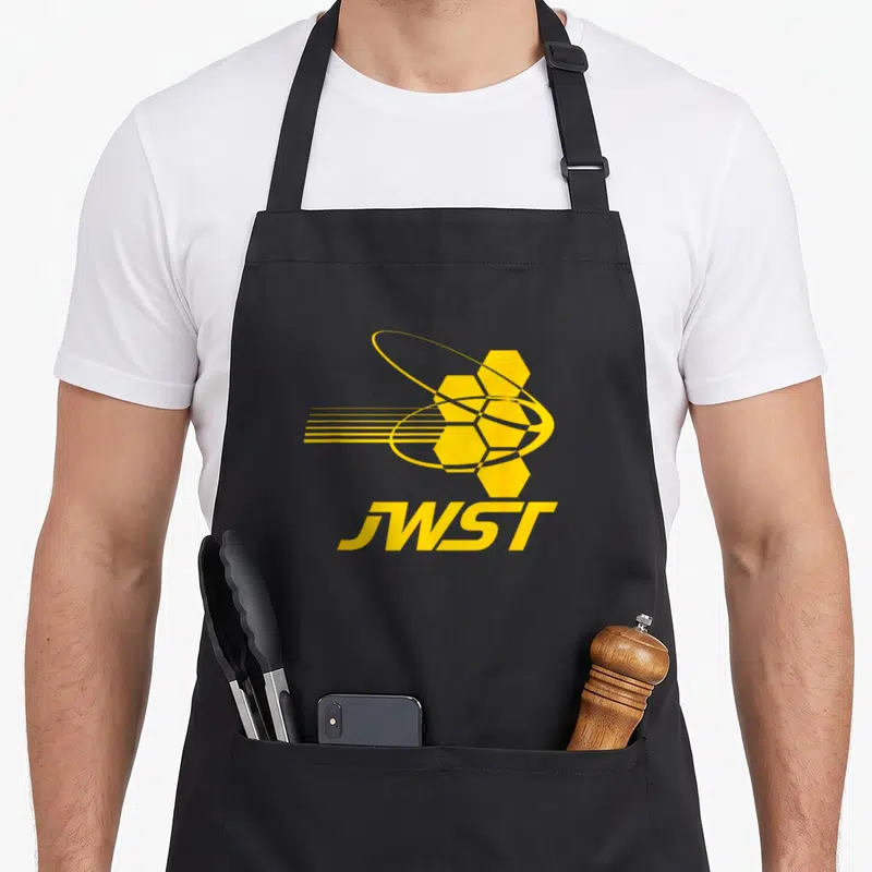 Tablier de cuisine noir avec logo JWST jaune représentant le télescope spatial et ses miroirs hexagonaux stylisés.