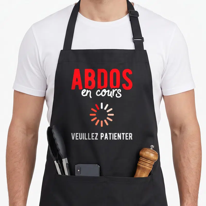 Tablier de cuisine noir avec inscription Abdos en cours et symbole de chargement rotatif rouge et blanc.