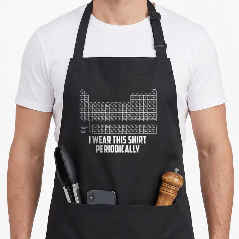 Tablier de cuisine noir avec tableau périodique des éléments et texte blanc en anglais.