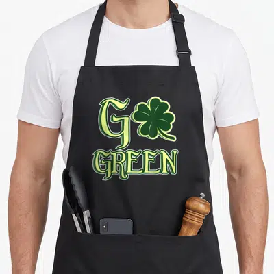 Tablier de cuisine noir avec l'inscription Go Green et un trèfle vert imprimé au centre.