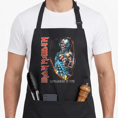 Tablier de cuisine noir avec illustration d'Eddie pointant une arme et le texte Iron Maiden vertical à gauche.