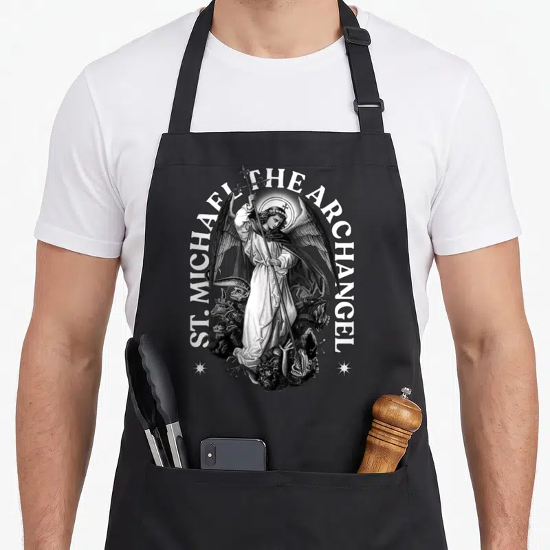 Tablier de cuisine noir avec illustration gravée de l'Archange Saint Michel tenant une lance au-dessus de démons et le texte ST. MICHAEL THE ARCHANGEL.