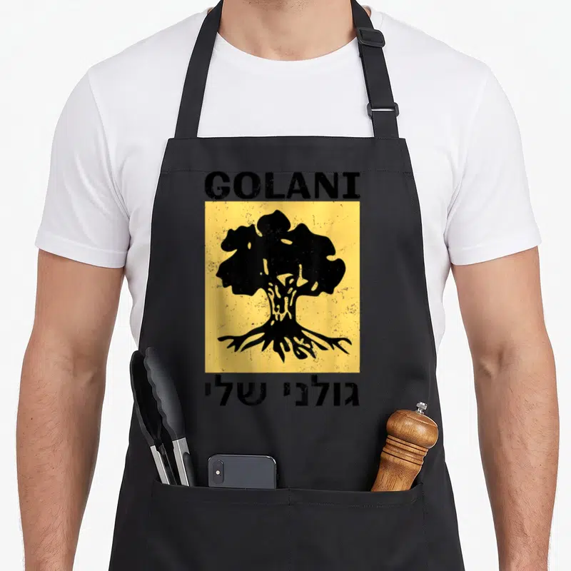 Tablier de cuisine noir avec insigne Golani, arbre stylisé noir sur fond jaune et texte en hébreu en bas.