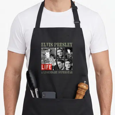 Tablier de cuisine noir avec collage Elvis Presley LIFE et texte A LEGENDARY SUPERSTAR en vert olive.