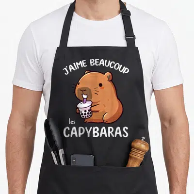 Tablier de cuisine noir avec illustration d'une capybara marron tenant une boisson aux perles et le texte j'aime beaucoup les capybaras.