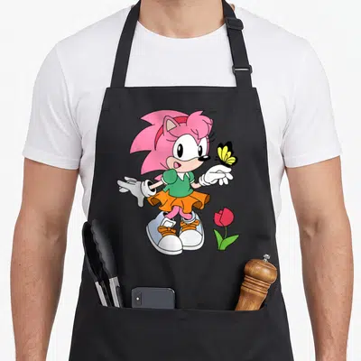 Tablier de cuisine noir avec illustration colorée d'un hérisson rose tenant un papillon jaune près d'une tulipe rouge.