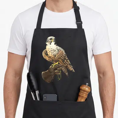 Tablier de cuisine noir avec un faucon perché sur un gant de fauconnerie marron et des lanières jaunes.