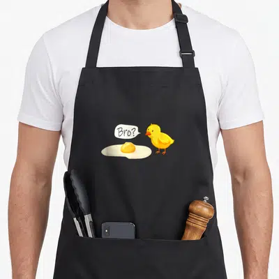 Tablier de cuisine noir avec un poussin jaune et un œuf frit portant la mention Bro ?