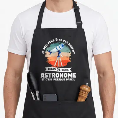 Tablier de cuisine noir avec illustration de télescope blanc et bleu sur fond de cercle dégradé orange et vert.