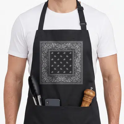 Tablier de cuisine noir avec motif bandana blanc à carreaux et motifs paisley détaillés sur le devant.