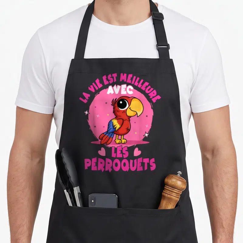 Tablier de cuisine noir avec un perroquet rouge et bleu sur fond rose et texte blanc