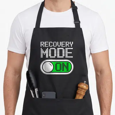 Tablier de cuisine noir avec l'inscription Recovery Mode et un bouton interrupteur vert activé sur fond uni.