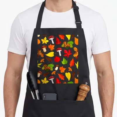 Tablier de cuisine noir avec des champignons, feuilles d'érable et noisettes imprimés en couleurs vives sur fond sombre.