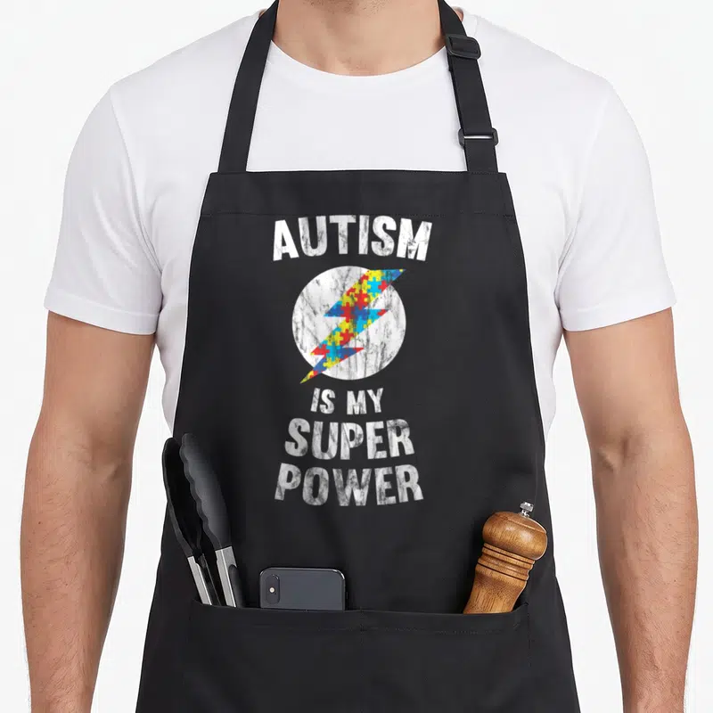 Tablier de cuisine noir avec inscription blanche et éclair multicolore en forme de puzzle.