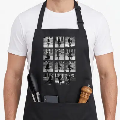 Tablier de cuisine noir avec douze vignettes montrant les silhouettes exagérées d'un homme en costume effectuant des pas ridicules.
