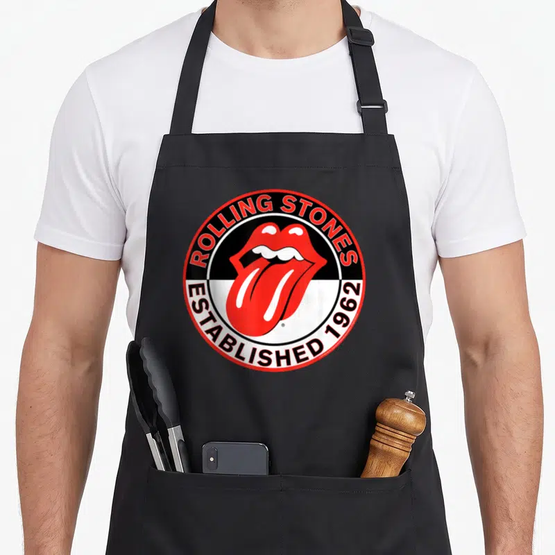 Tablier de cuisine noir avec l'emblème circulaire des Rolling Stones montrant une bouche rouge et les mots Established 1962.