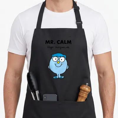 Tablier de cuisine noir avec illustration de Mr. Calm, personnage bleu souriant aux lunettes et signature Roger Hargreaves.
