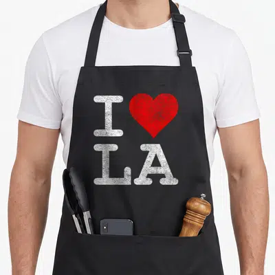 Tablier de cuisine noir avec un grand cœur rouge et les lettres I LA en blanc texturé.