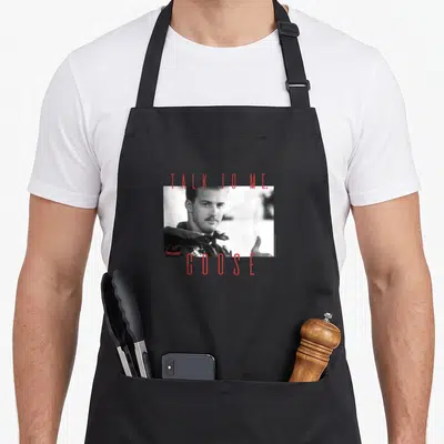 Tablier de cuisine noir avec portrait en noir et blanc de Goose et texte rouge Talk To Me Goose.