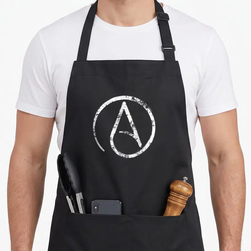 Tablier de cuisine noir avec symbole athée blanc en cercle, texture usée et style décontracté au centre du vêtement.