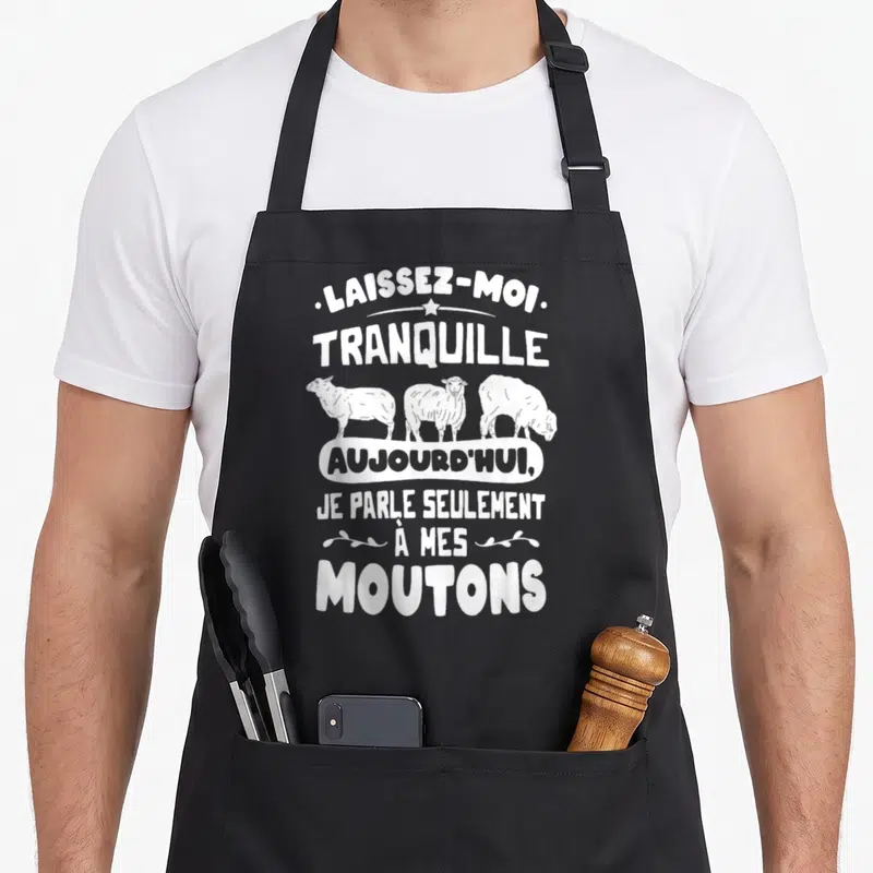 Tablier de cuisine noir avec le texte blanc Laissez-moi tranquille aujourd'hui je parle seulement à mes moutons au-dessus de trois moutons dessinés.