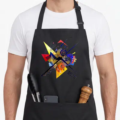 Tablier de cuisine noir avec reproduction d'une œuvre abstraite aux triangles jaunes, cercles bleus et lignes noires croisées.