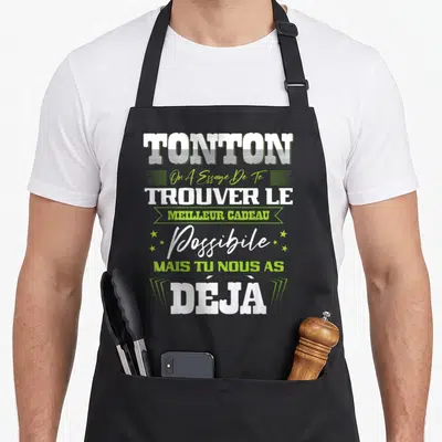 Tablier de cuisine noir avec l'inscription Tonton On A Essayé De Te Trouver Le Meilleur Cadeau Possible Mais Tu Nous As Déjà en vert et blanc.