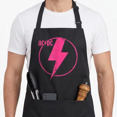 Tablier de cuisine noir avec un grand logo AC/DC rose vif et un éclair circulaire.