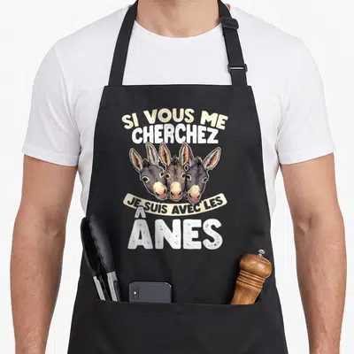 Tablier de cuisine noir avec trois têtes d'ânes et le texte Si Vous Me Cherchez Je Suis Avec Les Ânes imprimé au centre.
