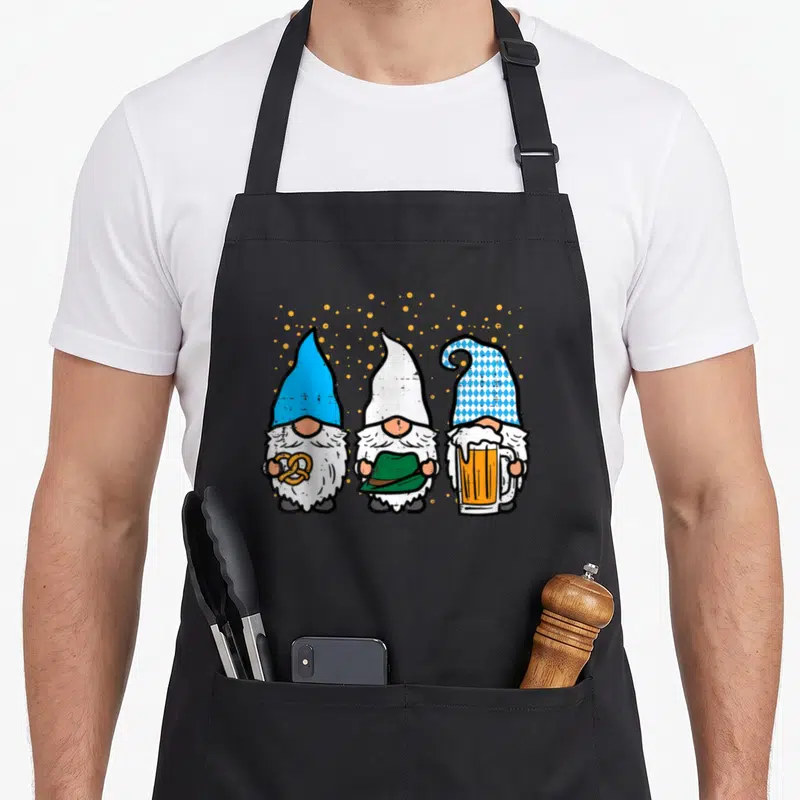 Tablier de cuisine noir avec trois gnomes bavarois tenant un bretzel, un chapeau et une bière.