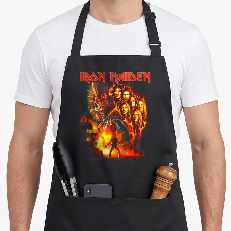 Tablier de cuisine noir avec le logo Iron Maiden et une illustration de Eddie enflammé entouré de visages.