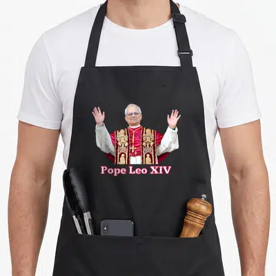 Tablier de cuisine noir avec portrait du pape Léon XIV levant les mains et texte Pope Leo XIV en rose.