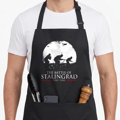 Tablier de cuisine noir avec silhouettes de soldats et avions au-dessus du texte The Battle of Stalingrad 1942-1943.