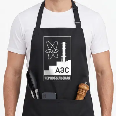 Tablier de cuisine noir avec logo atomique, tour industrielle et inscriptions russes A en blanc.