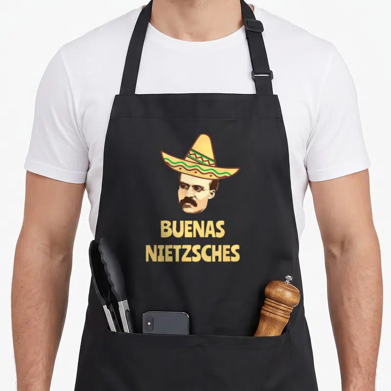 Tablier de cuisine noir avec tête de Nietzsche coiffé d'un sombrero et l'inscription Buenas Nietzsches en lettres jaunes.