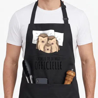 Tablier de cuisine noir avec une illustration de trois hérissons dans un lit et le texte « chemise de la nuit ».