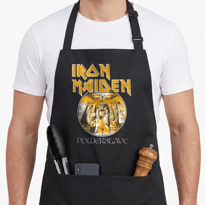 Tablier de cuisine noir avec le logo Iron Maiden et une illustration circulaire Powerslave aux teintes ocre et bleu marine.