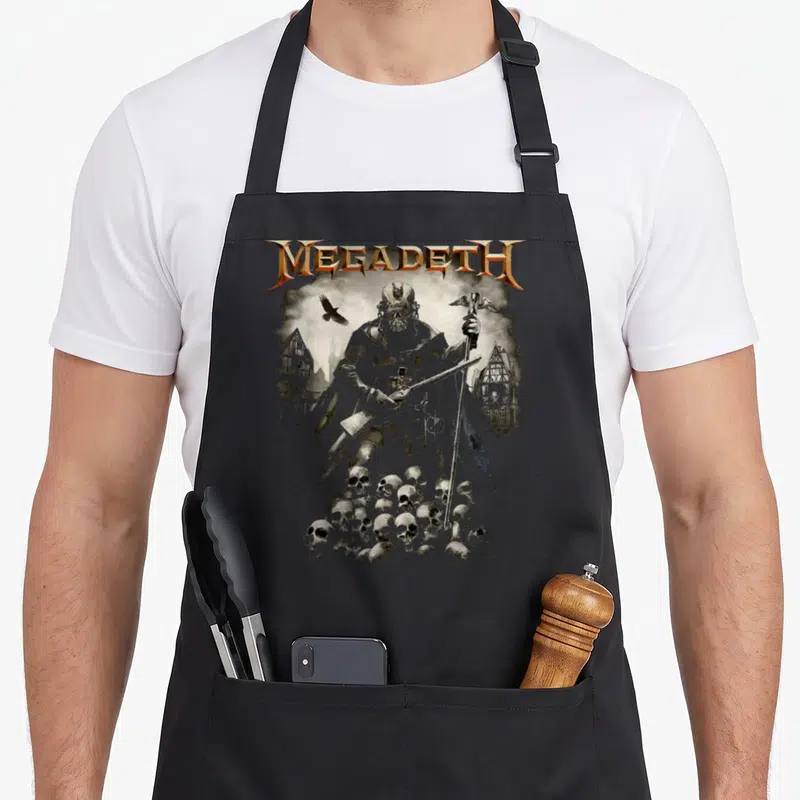 Tablier de cuisine noir avec illustration d'un personnage squelettique tenant une faux entouré de corbeaux et de skulls sous le logo Megadeth.