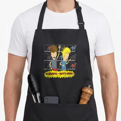 Tablier de cuisine noir avec Beavis et Butt-Head devant des logos MTV superposés et un bandeau jaune texturé.