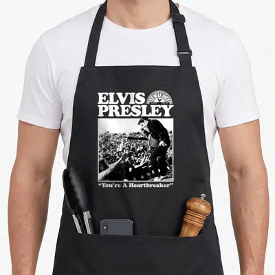 Tablier de cuisine noir avec une illustration Elvis Presley et le texte Vous êtes un brise-cœur imprimé en blanc.