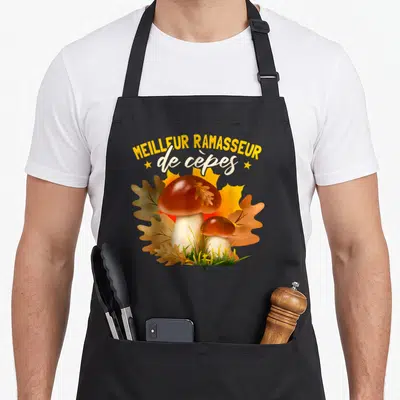 Tablier de cuisine noir avec illustration de cèpes et feuilles d'automne dorées.