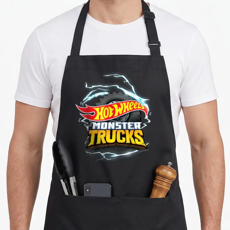 Tablier de cuisine noir avec logo Hot Wheels Monster Trucks entouré d'éclairs bleus et d'un gros pneu cranté.