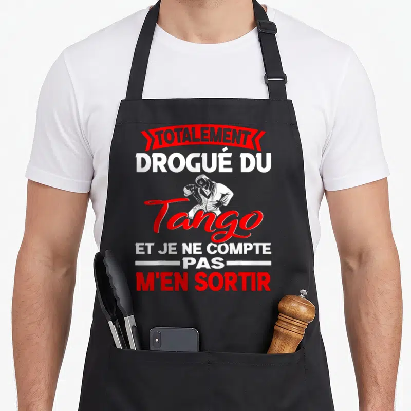 Tablier de cuisine noir avec une illustration de couple dansant le tango et un slogan humoristique en rouge et blanc.