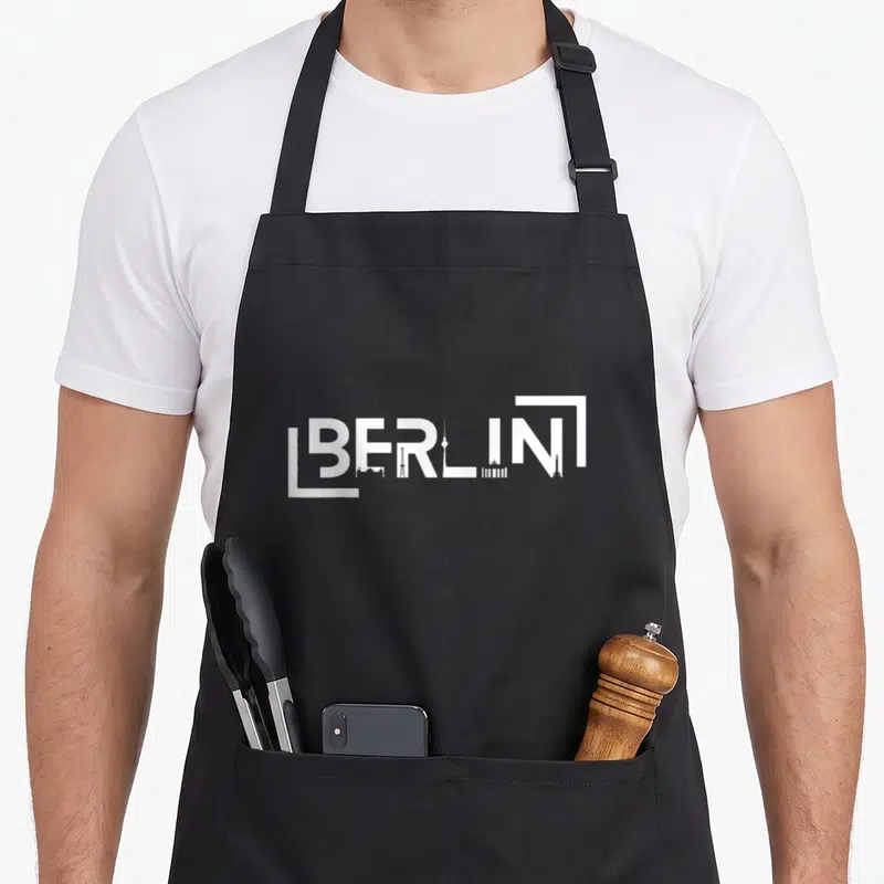 Tablier de cuisine noir avec inscription blanche BERLIN combinée à des silhouettes de tours et d'édifices emblématiques.