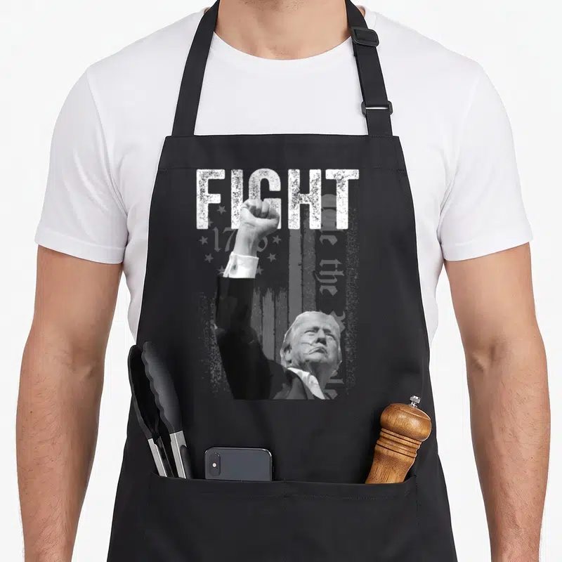 Tablier de cuisine noir avec illustration d'un poing levé et du texte FIGHT en blanc.