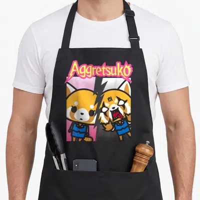 Tablier de cuisine noir avec illustration colorée d'Aggretsuko montrant ses deux visages opposés sous le titre stylisé.