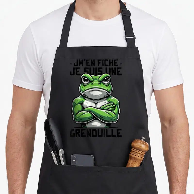 Tablier de cuisine noir avec une illustration de grenouille verte aux bras croisés et du texte en lettres noires.