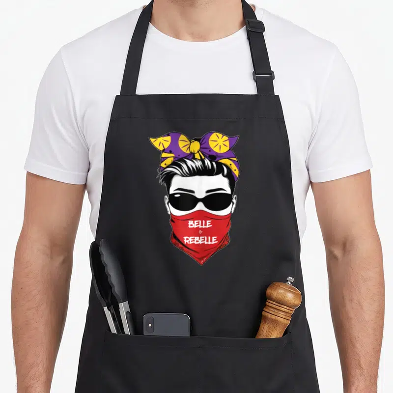 Tablier de cuisine noir avec illustration femme lunettes noires bandana rouge et nœud violet jaune, texte Belle & Rebelle.