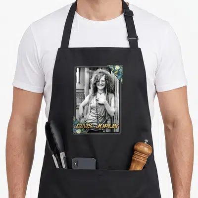 Tablier de cuisine noir avec portrait vintage de Janis Joplin et décorations florales dans les angles.