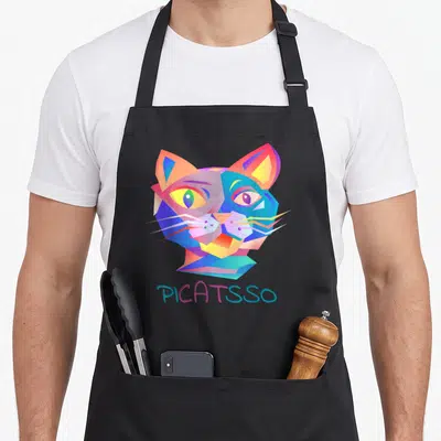 Tablier de cuisine noir avec tête de chat géométrique multicolore et texte PICATS en bas.